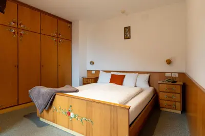 a bedroom with a large bed and wooden cabinets at Albergo Pensione Serenetta in Varena