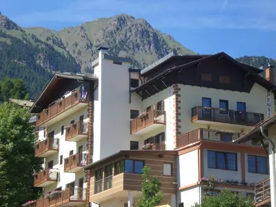 a building with balconies and mountains in the background at Albergo Pensione Serenetta in Varena