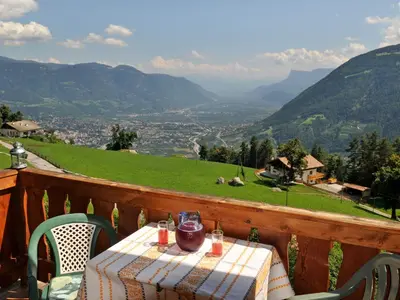 a table on a balcony with a view of a valley at Haus Gilli in Lagundo