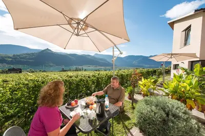 a man and woman sitting at a table under an umbrella at Weingut Morandell in Caldaro