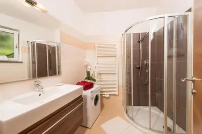 a bathroom with a sink and a shower and a washing machine at Weingut Morandell in Caldaro