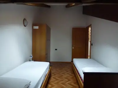 a room with two beds and a cabinet at Casa Angela in Predazzo