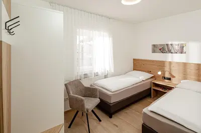 a bedroom with a bed and a chair and a window at Prälatenhof Wine & Apartments in Caldaro