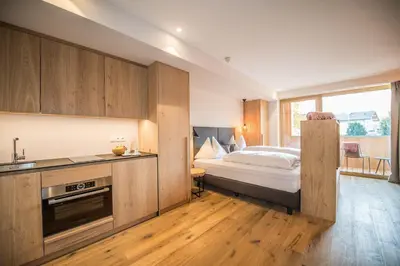 a bedroom with a bed and a kitchen with a sink at Dining & Living Alpenrose in Bressanone