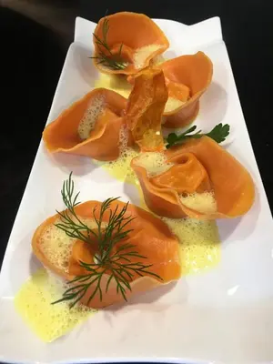 a white plate of food with orange food on it at Dining & Living Alpenrose in Bressanone