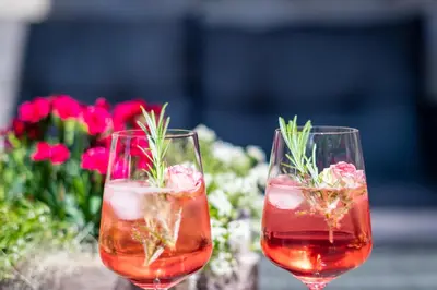 two wine glasses with rosemary in them next to flowers at Pension Etschblick B&B in Frangarto