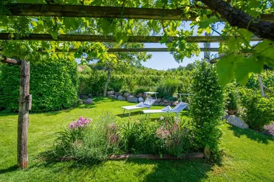 a garden with a pergola and chairs and flowers at Pension Etschblick B&B in Frangarto