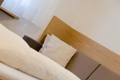 a bed with a wooden head board with a pillow at Pension Etschblick B&B in Frangarto