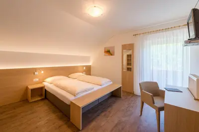 a bedroom with a bed with a desk and a chair at Pension Etschblick B&B in Frangarto