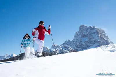 two people are skiing down a snow covered mountain at Hotel Orso Grigio in Selva di Cadore