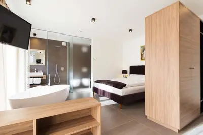 a bathroom with a tub and a bed and a television at Apartments Sissi & Franz in Merano