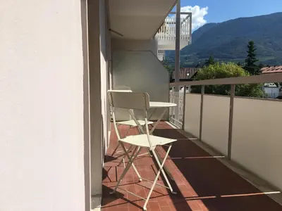 a white chair sitting on the balcony of a house at Apartments Sissi & Franz in Merano