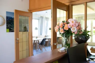 a table with a cup of coffee and a vase with purple flowers at Residence Margreth in Marlengo