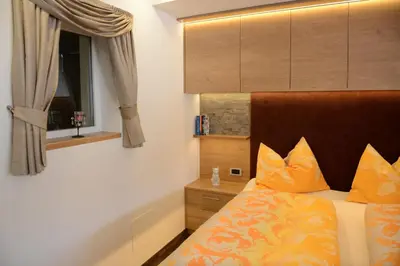 a bedroom with a bed with orange pillows and a window at Apartments Mujnei in Santa Cristina in Val Gardena