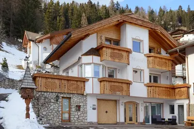 a house with wooden balconies on a mountain at Apartments Mujnei in Santa Cristina in Val Gardena