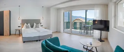 a bedroom with a bed and a living room with a balcony at FELDHOF - Agri-apartment-suites in Termeno