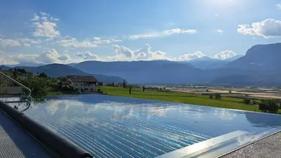 a large swimming pool with a view of mountains at FELDHOF - Agri-apartment-suites in Termeno