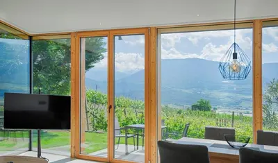 a living room with a television and a table with chairs at FELDHOF - Agri-apartment-suites in Termeno
