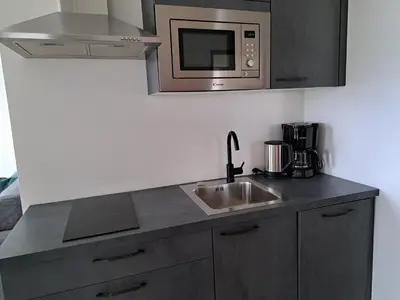 a kitchen with a sink and a microwave at FELDHOF - Agri-apartment-suites in Termeno