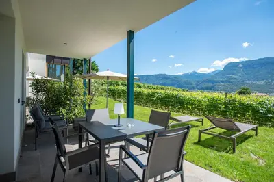a table and chairs on a patio with a view at FELDHOF - Agri-apartment-suites in Termeno