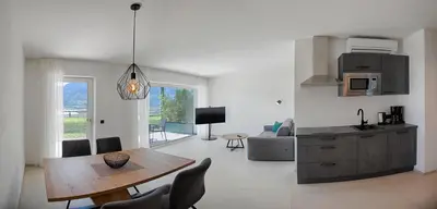 a living room with a dining table and a kitchen at FELDHOF - Agri-apartment-suites in Termeno