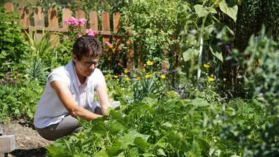 a woman squatting in a garden planting plants at Alpegger in Terento