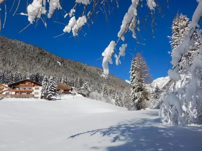 a snow covered mountain with a house in the background at Alpegger in Terento