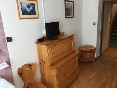 a room with a tv on top of a wooden dresser at Hotel Fiames in Cortina dʼAmpezzo