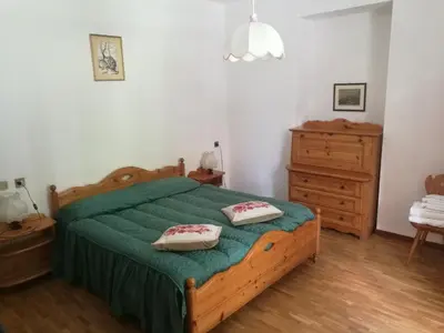 a bedroom with a green bed with two pillows on it at Hotel Fiames in Cortina dʼAmpezzo