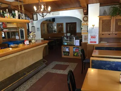 a restaurant with a bar and some tables and chairs at Hotel Fiames in Cortina dʼAmpezzo