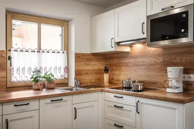 a kitchen with white cabinets and a sink and a window at Pradel Dolomites in San Martino in Badia