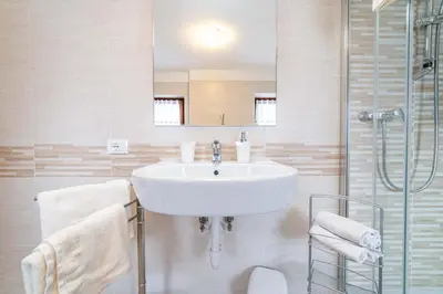 a white bathroom with a sink and a shower at Ospitalità Diffusa Laste Dolomites - Cèsa Murer in Pallua