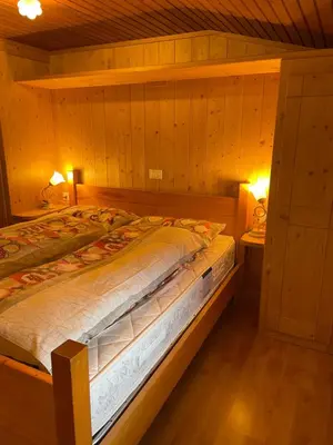 a bed in a wooden room with two night stands at Ospitalità Diffusa Laste Dolomites - Cèsa Murer in Pallua