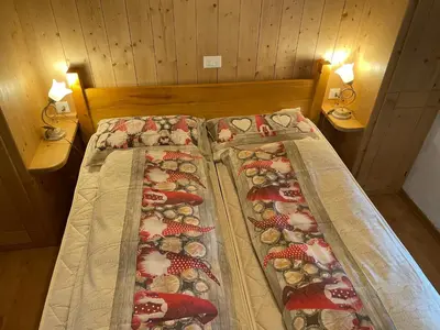 a bed in a room with two lamps on two tables at Ospitalità Diffusa Laste Dolomites - Cèsa Murer in Pallua