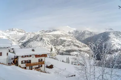 a snow covered mountain with a house in the foreground at Ospitalità Diffusa Laste Dolomites - Cèsa Murer in Pallua
