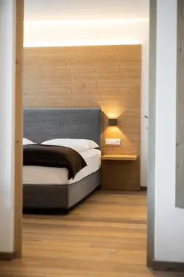 a bedroom with a large bed with a wooden headboard at Villa David Dolomites in Selva di Val Gardena