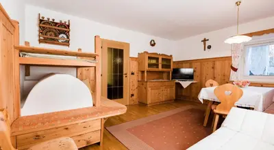 a room with a bed and a table and a tv at Pramulin in Selva di Val Gardena