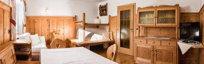 a room with a kitchen with wooden cabinets and a television at Pramulin in Selva di Val Gardena