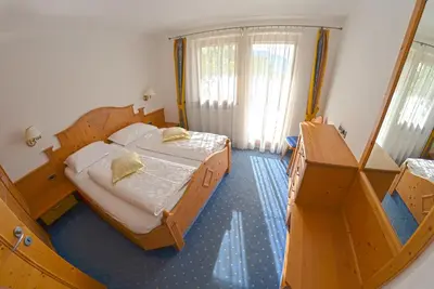 a bedroom with two beds and a large window at Hammele Appartements in Schenna