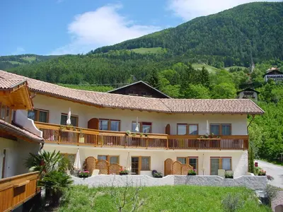 a large building with a mountain in the background at Hammele Appartements in Schenna