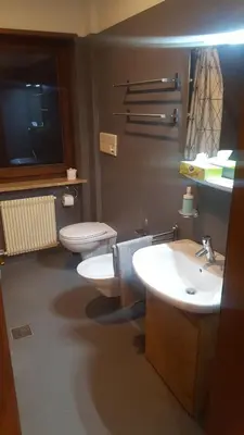 a bathroom with two sinks and a toilet and a tv at SonnenApartment in Lana