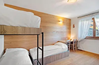 a bedroom with two bunk beds and a desk at Sunny Arabba Apartment in Arabba