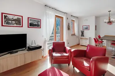 a living room with red chairs and a flat screen tv at Sunny Arabba Apartment in Arabba