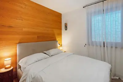 a bedroom with a white bed with a wooden wall at Sunny Arabba Apartment in Arabba