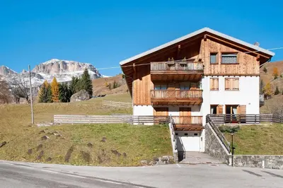 a house on a hill with a mountain in the background at Sunny Arabba Apartment in Arabba