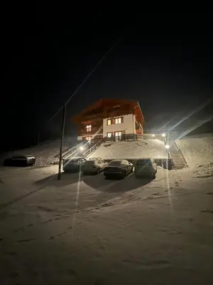 three cars parked in a parking lot in the snow at night at Sunny Arabba Apartment in Arabba
