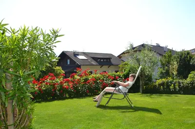 a woman sitting in a chair in a garden at Haus Marion in Appiano sulla Strada del Vino