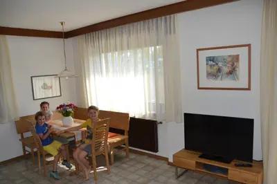 three children sitting at a table in a living room at Haus Marion in Appiano sulla Strada del Vino