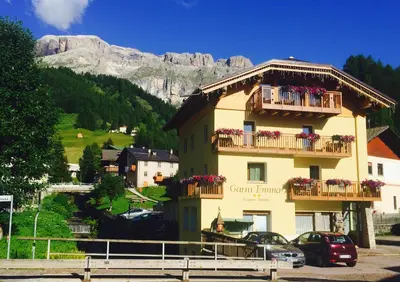 a building with balconies and cars parked in a parking lot at Garní Emma in Arabba