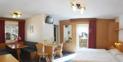 a hotel room with a bed and a table and a desk at Garní Emma in Arabba